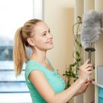 happy woman with duster cleaning at home